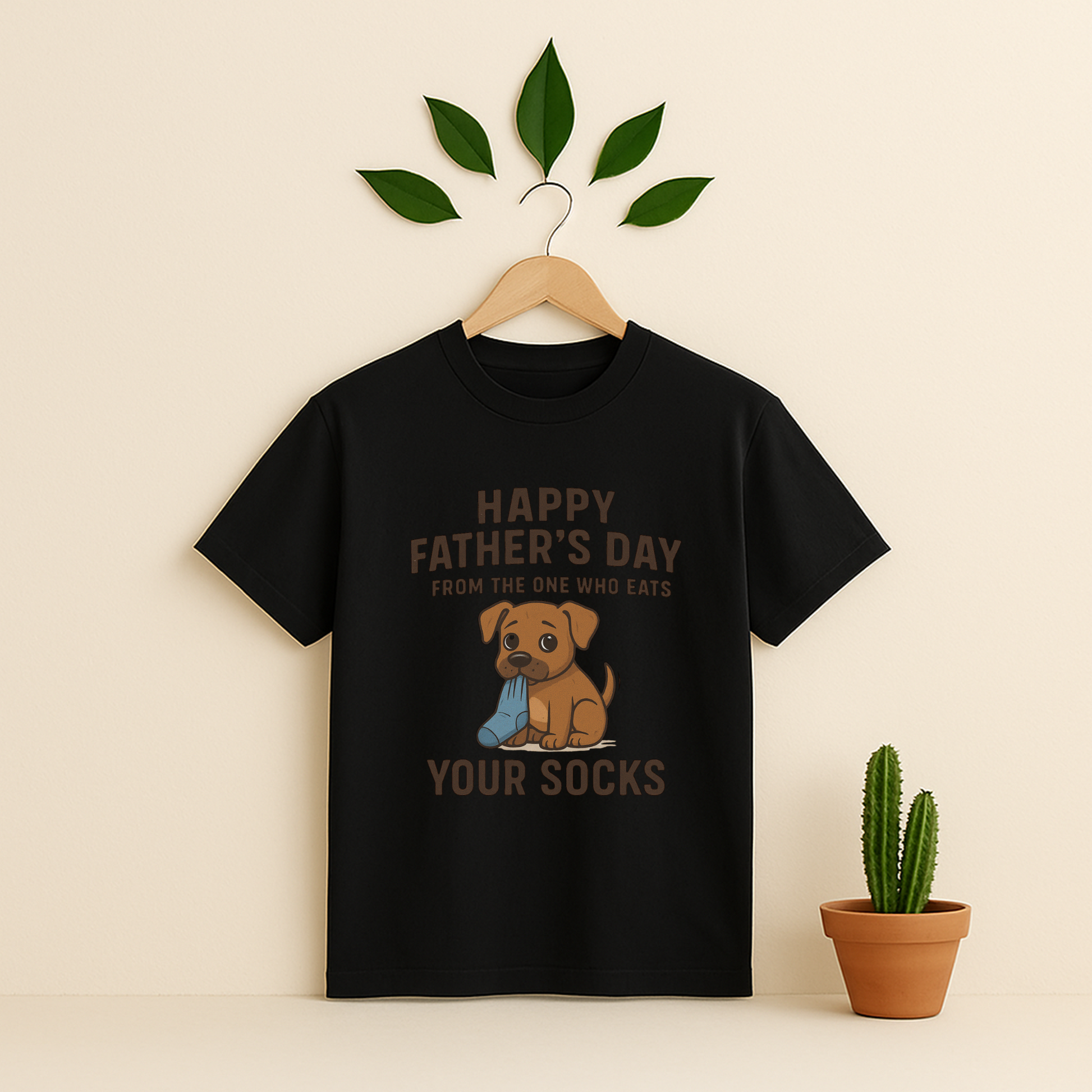 Black t-shirt with graphic antd text on a wooden hanger against a beige background with a cactus plant.