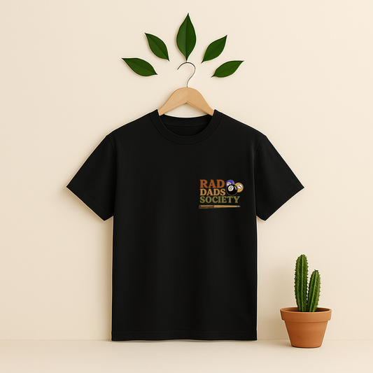 Black t-shirt with 'Rad Dads Society' graphic on a wooden hanger against a beige background with a cactus plant.
