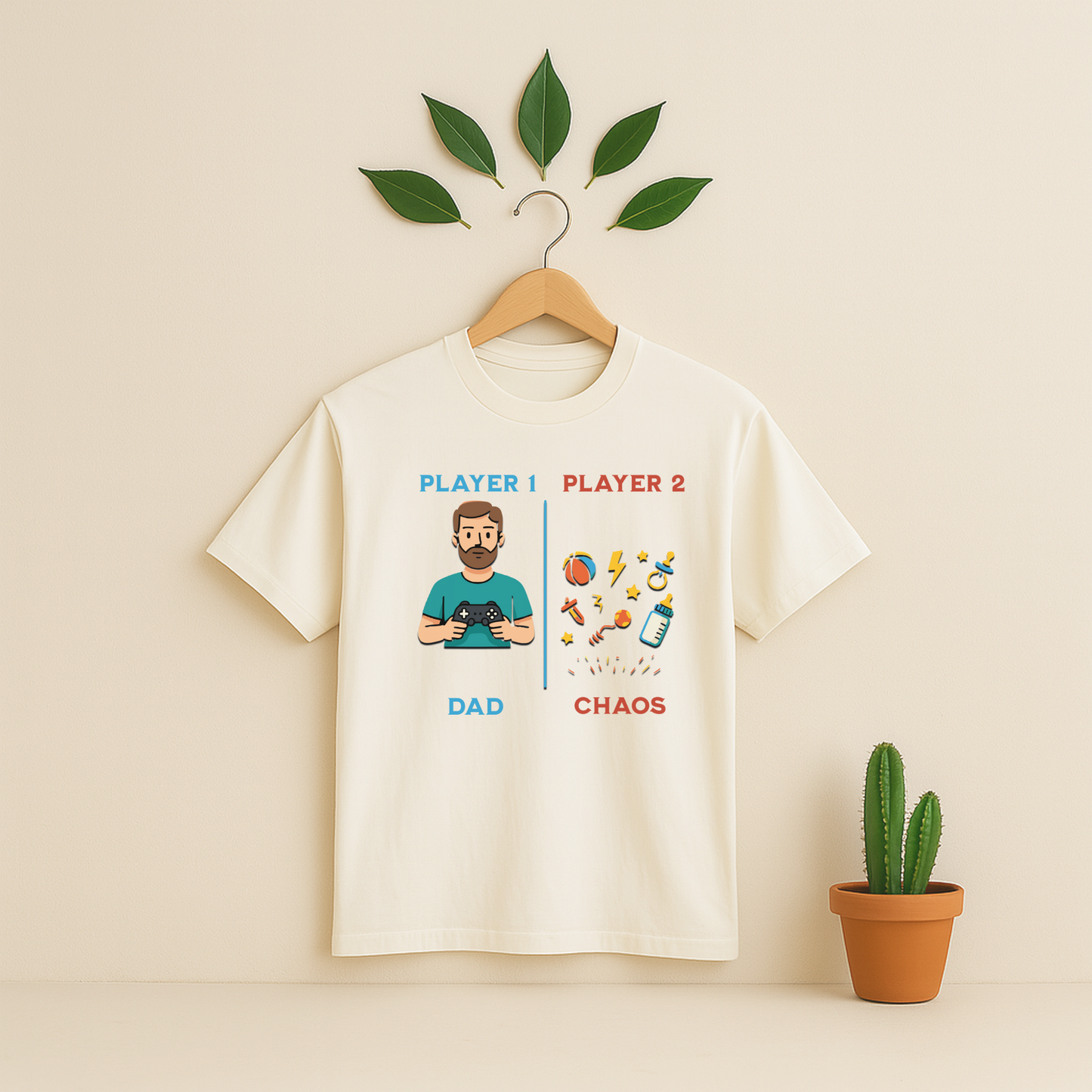 Ivory t-shirt with 'Player 1 & Player 2 Dad' graphic on a wooden hanger against a beige background with a cactus plant.