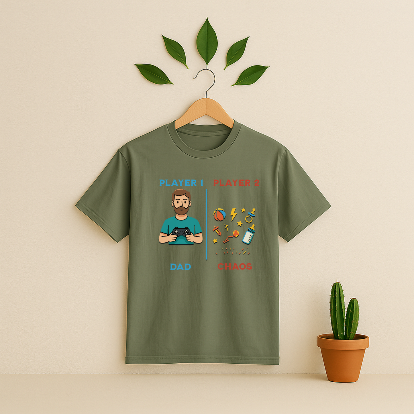 Moss t-shirt with 'Player 1 & Player 2 Dad' graphic on a wooden hanger against a beige background with a cactus plant.