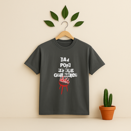 Pepper t-shirt with 'Dad Pops Grill Master' graphic on a wooden hanger against a beige background with a cactus plant.