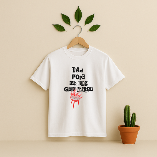 White t-shirt with 'Dad Pops Grill Master' graphic on a wooden hanger against a beige background with a cactus plant.