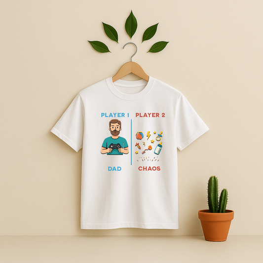 White t-shirt with 'Player 1 & Player 2 Dad' graphic on a wooden hanger against a beige background with a cactus plant.
