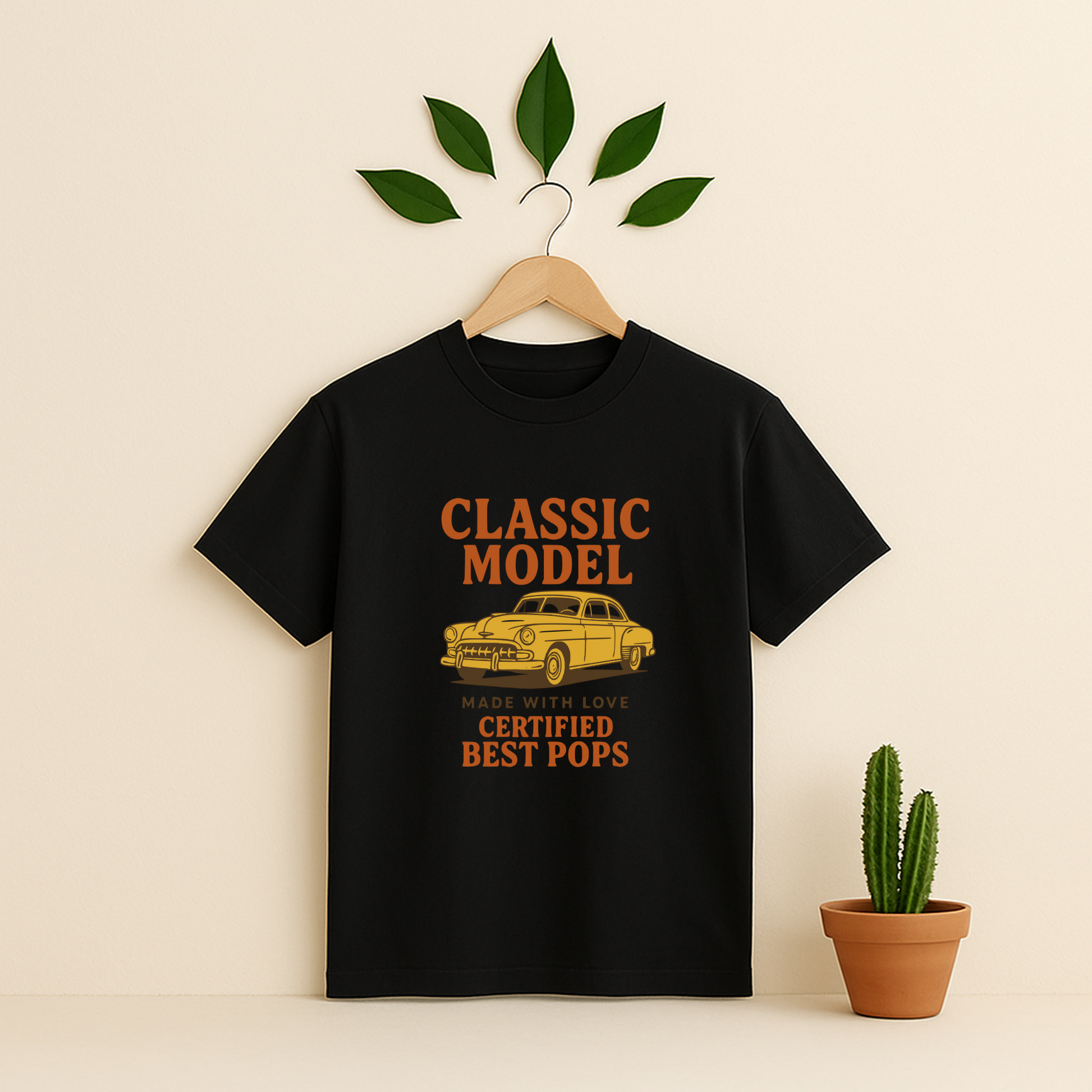 Black t-shirt graphic and text on a wooden hanger against a beige background with a cactus plant.